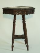 An early 20th century Anglo Indian carved hexagonal table, with splayed legs linked by a shelf,