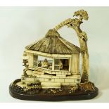 A late 19th century ivory and horn okimono, of two figures seated  in a dwelling with arched tree,