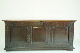 A 17th century oak coffer with triple panelled front and carved frieze, 64cm high, 147cm wide,