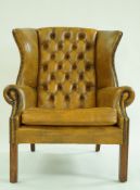 A 20th century leather wingback armchair, with button back,
