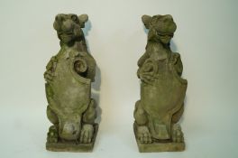 A pair of cast heraldic dogs, each holding a shield on a rectangular plinth,