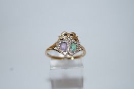 An amethyst, emerald and diamond 9 carat gold lovers hearts ring, with a ribbon bow surmount,