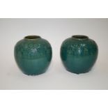 A pair of Chinese earthenware vases each moulded with a translucent green glaze, 21cm high,