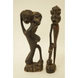 A carved African figure of a beast holding a head,