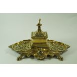 A Victorian brass desk stand, with central inkwell, pierced sides and dual pen rests, on claw feet,