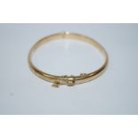 A 9ct gold hinged bangle, of hollow D section and half engraved, 0.5 cm wide, internal diameter 6.