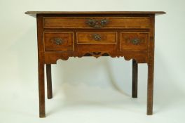 A George III oak cross banded low boy with one long drawer above two deep short drawers flanking a