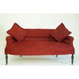 An Edwardian two seat sofa with low back, on turned ebonised legs with brass and ceramic casters,