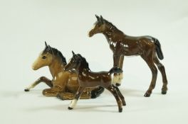 Two Beswick figures of dark bay foals, printed marks in black and another lying down,