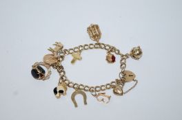 A 9ct gold bracelet, of double curb links, to a padlock clasp, with charms attached, 25.