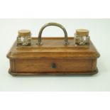 An oak desk stand with central brass handle, two square inkwells and a frieze drawer, 30.