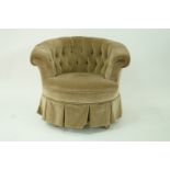 An Edwardian tub shaped drawing room chair upholstered and standing on walnut turned supports