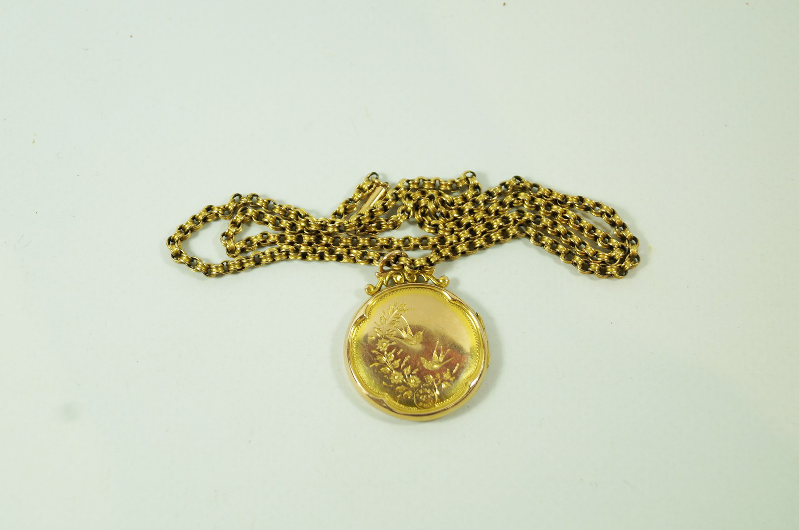 A locket, of circular outline, 2.7 cm diameter; on a chain tagged '9c', 45 cm long, 3.