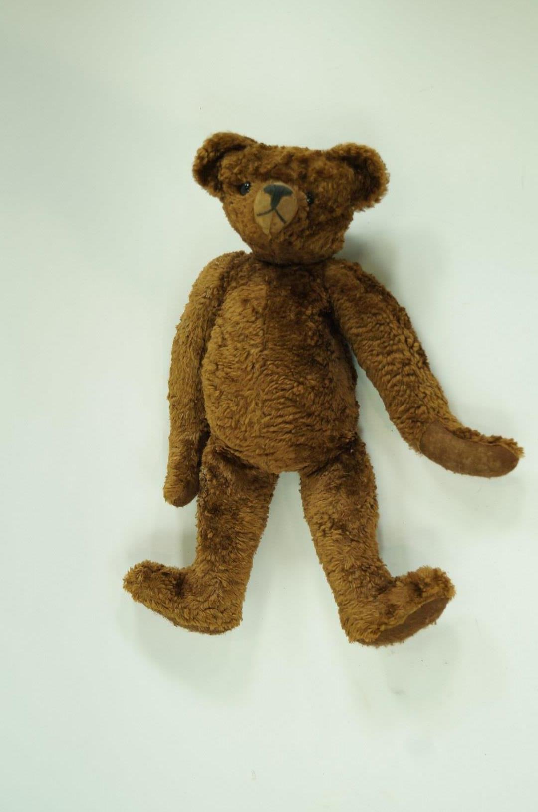 A straw filled teddy bear, with brown plush fur and felt pads,