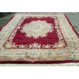 A Chinese carpet with central flower medallion, on a dark red field within one wide border,