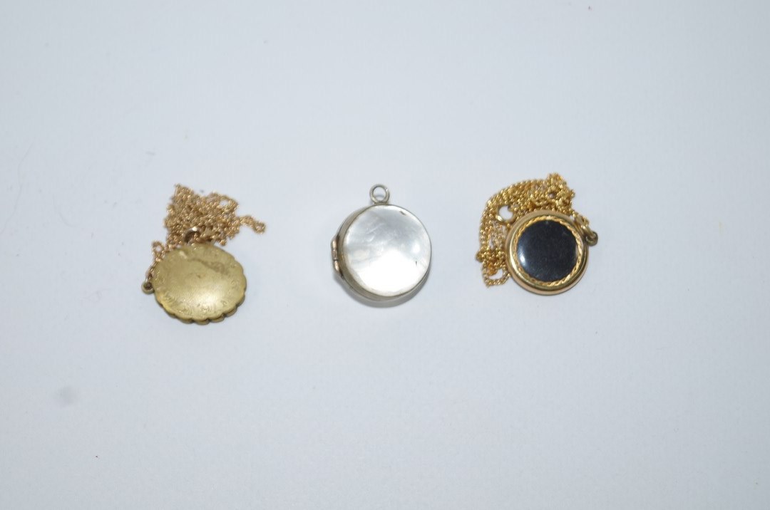 A metal locket on a 9ct gold chain; an enamelled locket on gilt chain;