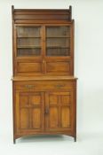 An Edwardian mahogany aesthetic movement side cabinet with two glazed doors above a horizontal