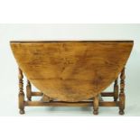 A large oak oval drop leaf dining table on turned legs linked by rectangular stretchers, 74cm high,