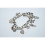 A silver bracelet, of solid curb links, with charms attached,