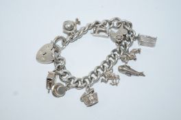 A silver bracelet, of solid curb links, with charms attached,