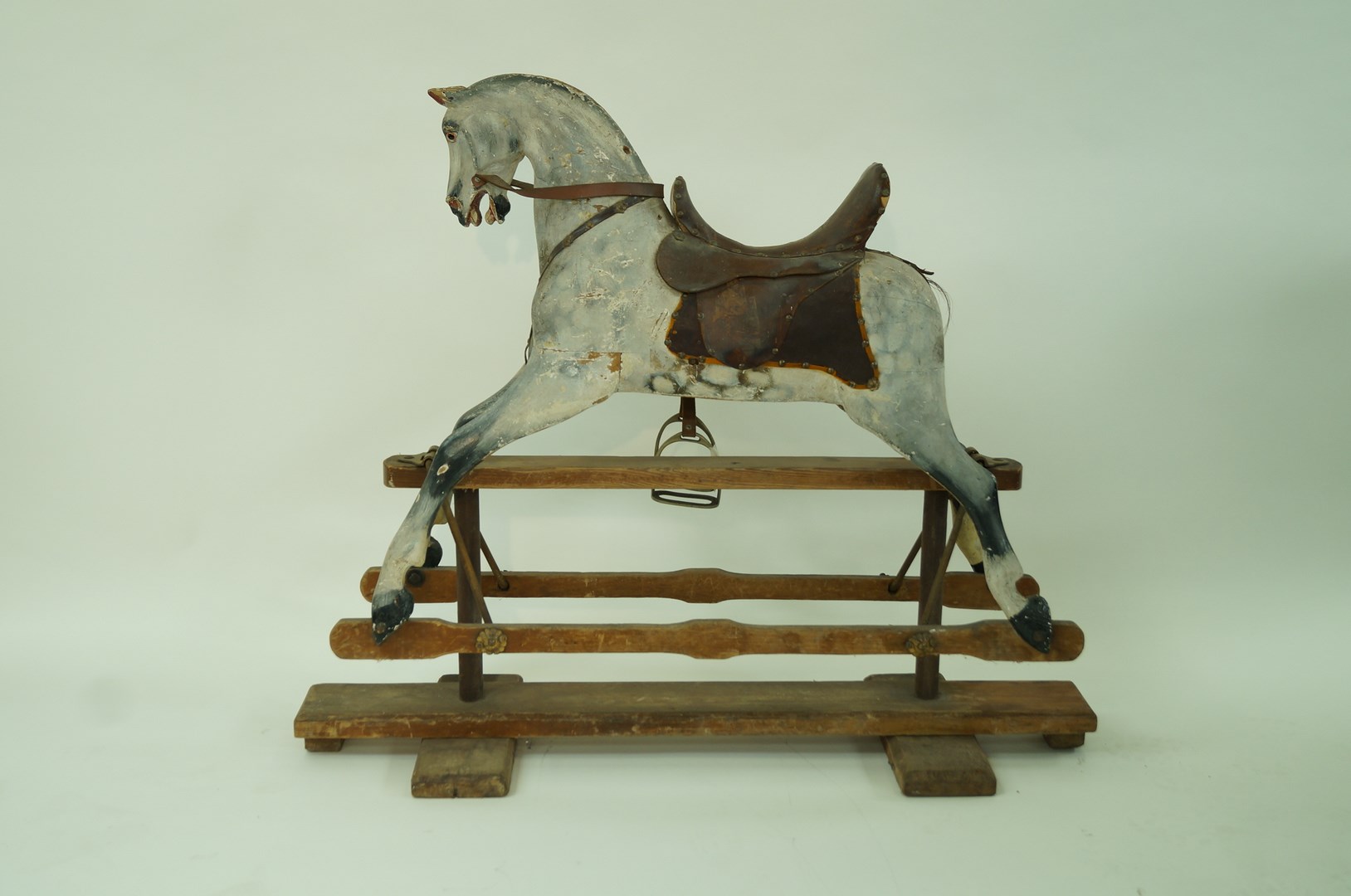 A Victorian carved wood and painted rocking horse on stand with leather saddle, 96cm high,