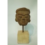 A Burmese terracotta model of a head mounted on a plinth,