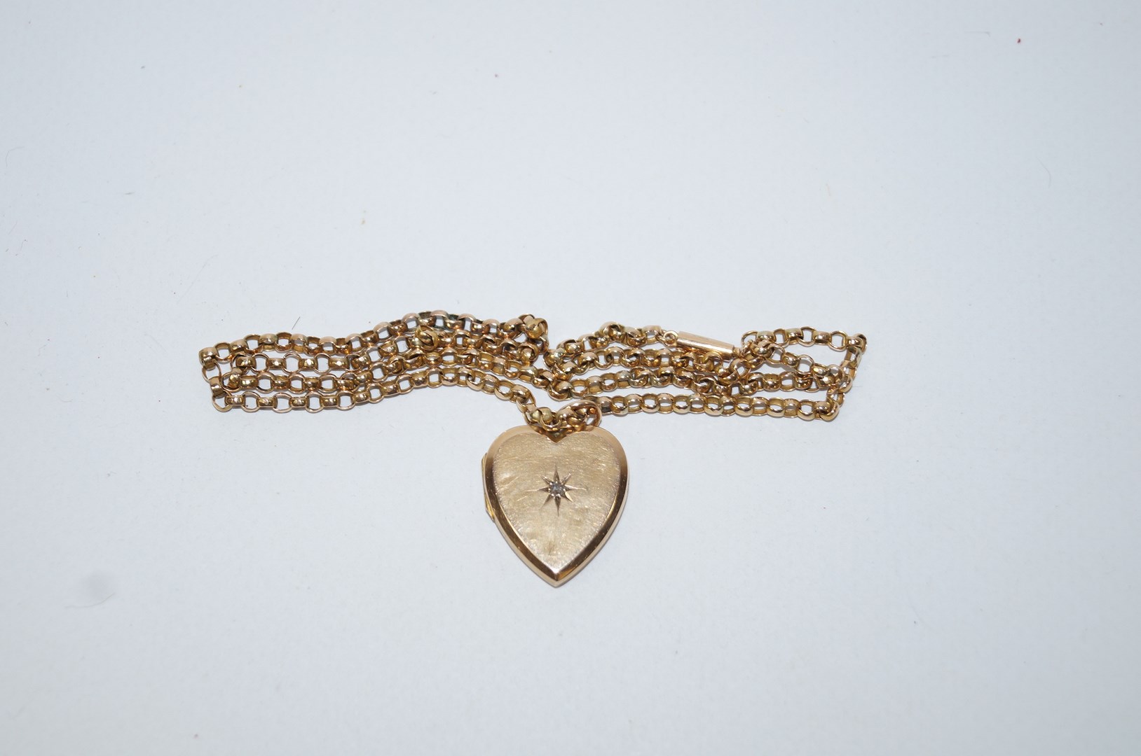 A heart shaped locket set with a rose cut diamond, 2 cm across; on a belcher link chain,