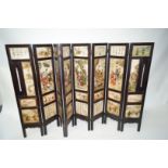 An early 20th century Chinese screen in eight folding sections inset with painted soap stone panels,