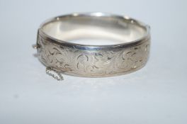 A silver hinged bangle, half engraved decoration, 1.