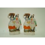 Two Staffordshire pottery figures of a lady holding a basket and her companion,