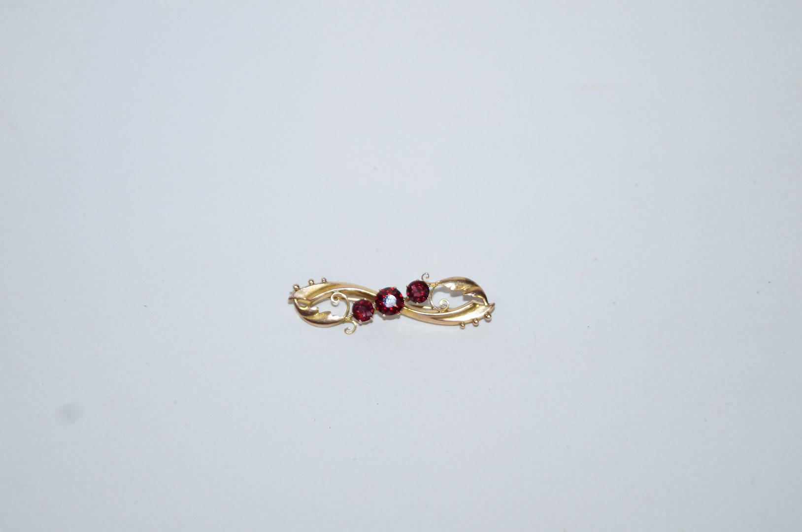 A 9 carat gold garnet brooch, Chester 1907, the trio of graduated stones to a scroll mount, 2.