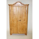 A pine armoire with arched crest and two doors on angled feet, 188cm high, 200cm wide,