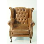 A leather button back wing armchair on cabriole legs