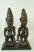 Two carved wooden tribal figures, set on a modern stained pine plinth, 28.