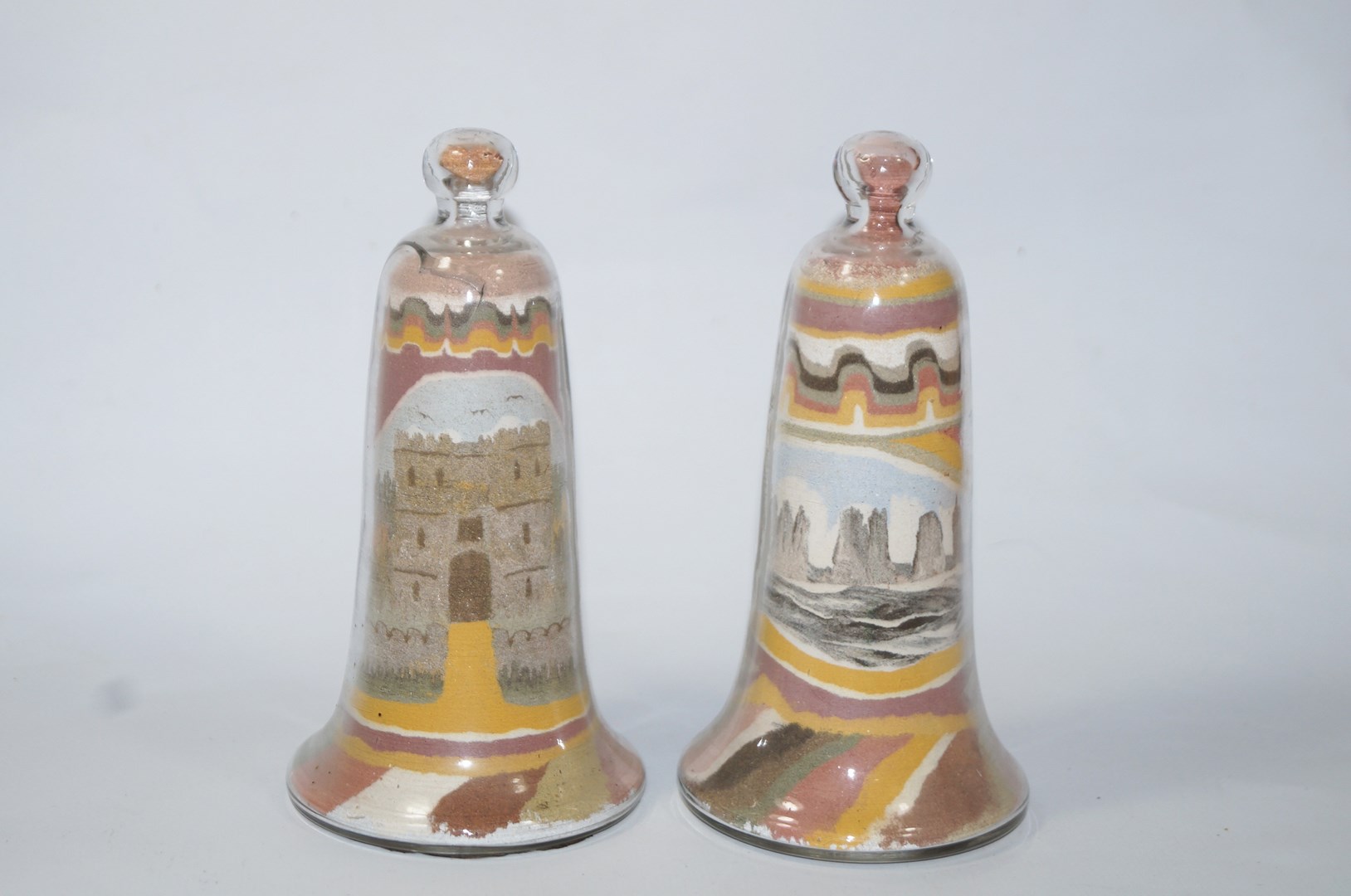 A pair of Victorian Isle of White Alum Bay sand bells depicting Carisbrook Castle and the other