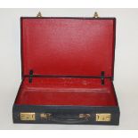 A black leather rectangular brief case, with red leather effect interior, 40.5cm wide, 28cm long, 8.