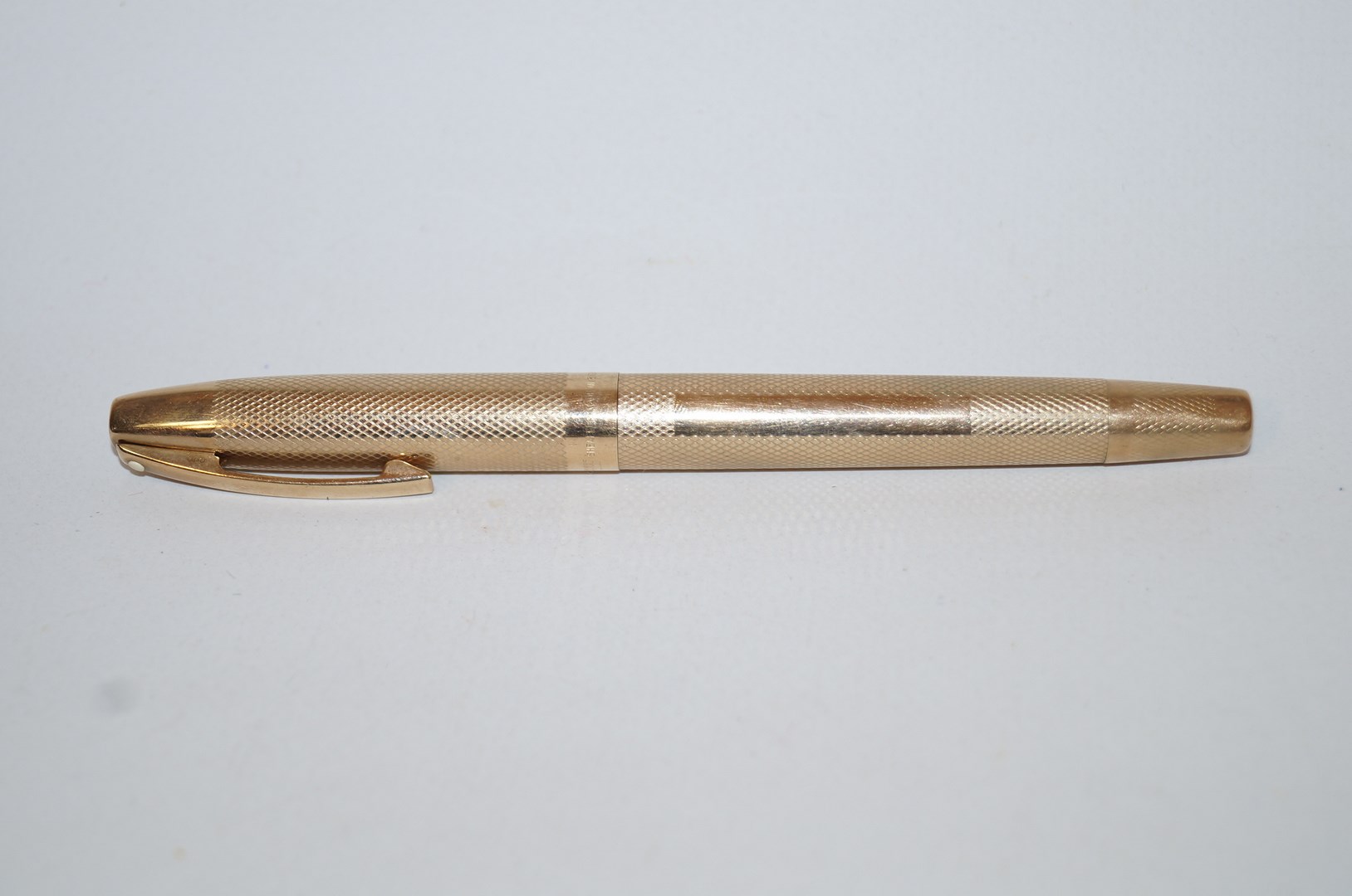 A gold Sheaffer pen in an engine turned 9 carat gold case with a 14k nib,