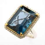 Blue Topaz, Diamond, 14k Gold Ring. Centering one emerald-cut blue topaz weighing approximately 17.