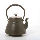 A Tetsubin The cast iron tea kettle is decorated with a scrolling diaper ground, with a Nanbu