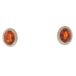 Pair of Garnet, Diamond, 14k White Gold Earrings. Each features one oval-cut garnet weighing