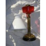 A brass column oil lamp with cranberry reservoir and white glass shade