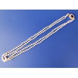A double strand graduated pearl necklace with 9ct gold cluster clasp having central garnet, 18”