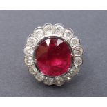 A large ruby & diamond cluster ring, the collet set oval cut pigeon-blood ruby weighing