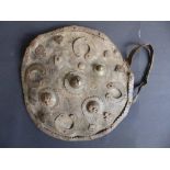 An 18th/19thC Indian hide shield with metal mounts, 12” diameter
