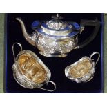 An Edwardian cased silver three piece silver tea service, of London shape embossed flowers and
