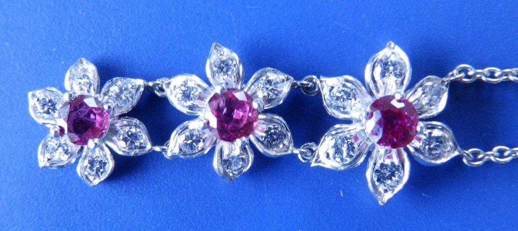 A ruby & diamond triple flowerhead cluster pendant necklace in white metal