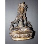 An antique brass Tibetan figure of a seated god, 8”