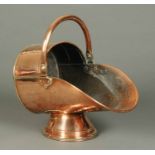 A Victorian copper coal helmet, with loop handle and circular socle base.