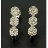 A pair of diamond ear studs, each with three small diamonds to illusion setting.