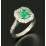 An 18 ct white gold Columbian emerald and diamond cluster ring, emerald 1.27 carats, diamonds 1.